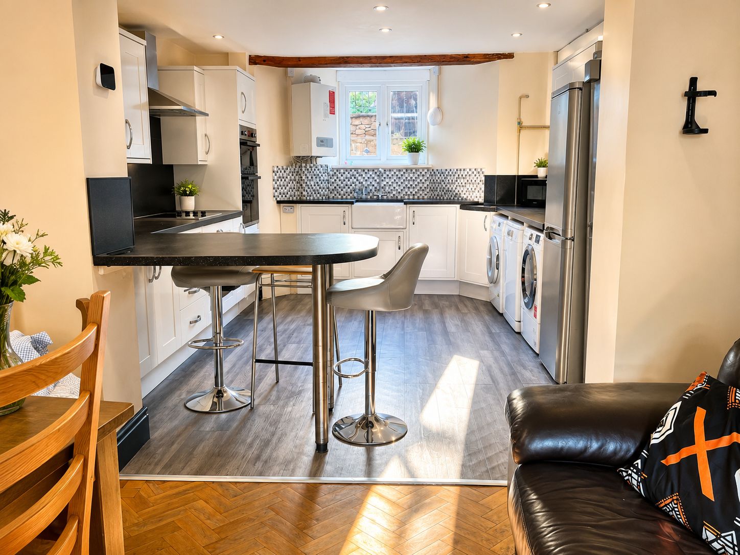 Home 17 Modern open plan kitchen with white cabinets, breakfast bar, chrome stools and integrated appliances in Lancaster student accommodation