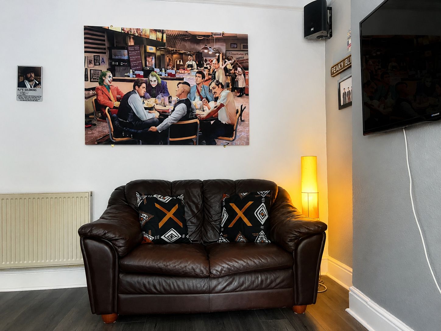 Home 2 Brown leather sofa with patterned cushions in a student accommodation lounge with Peaky Blinders poster and wall-mounted TV